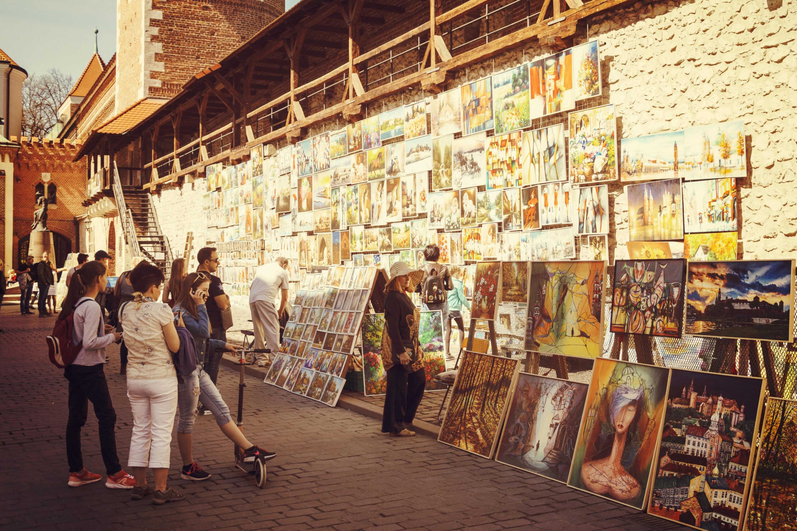 Street art gallery with people browsing vibrant paintings in daylight.
