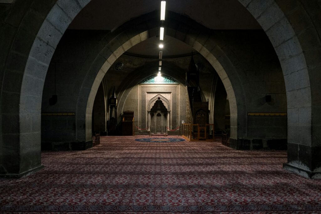 Intricate archways and carpeted floors inside a historic mosque, showcasing architectural elegance.