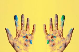 Colorful fingers spread against a bright yellow backdrop, showcasing creativity.