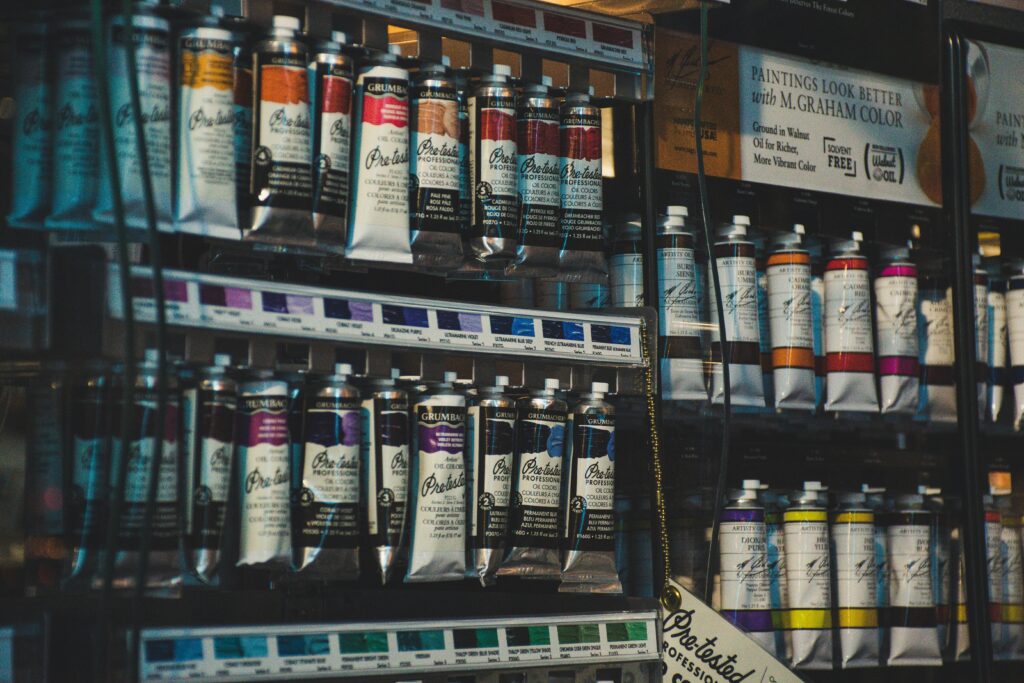 Vibrant art store aisle featuring a row of colorful professional paint tubes on display shelves.